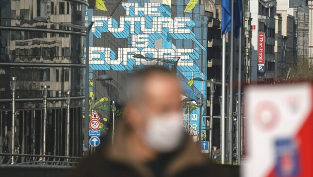 Ein Mann mit Maske vor dem Gebäude der EU-Kommission in Brüssel (Bild: AFP)