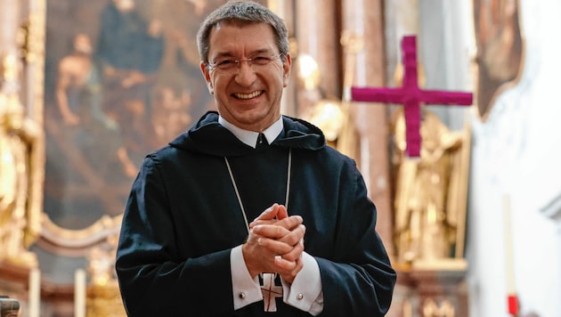 Erzabt Korbinian Birnbacher vor dem mit Stoff bedeckten Altarkreuz in der Stiftskirche St. Peter in Salzburg, das hoch oben im Kirchenraum schwebt. (Bild: Markus Tschepp)