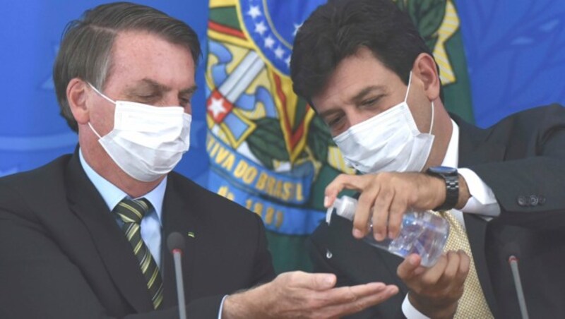 Luiz Henrique Mandetta (re.) desinfiziert Präsident Bolsonaro die Hände - er forderte stets striktere Maßnahmen im Kampf gegen das Virus. (Bild: AP)