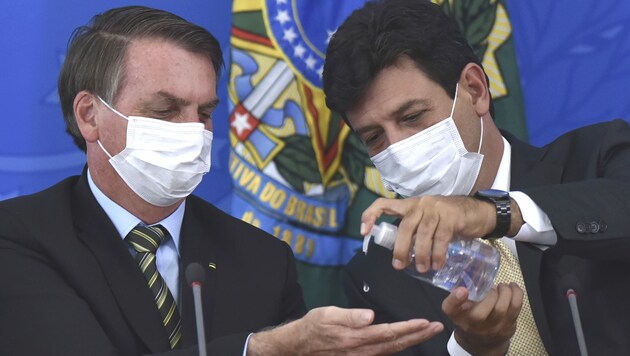 Luiz Henrique Mandetta (re.) desinfiziert Präsident Bolsonaro die Hände - er forderte stets striktere Maßnahmen im Kampf gegen das Virus. (Bild: AP)