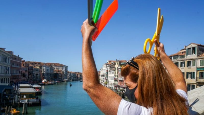 Eine Friseurin beteiligt sich an einem Flashmob auf der Rialto-Brücke in Venedig, um für die Wiederöffnung ihres Geschäfts zu demonstrieren. (Bild: AFP)