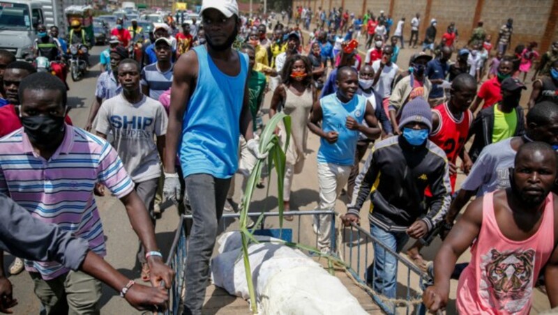 Bewohner der kenianischen Hauptstadt Nairobi demonstrieren mit der Leiche eines Mannes, der laut ihren Angaben von der Polizei zu Tode geprügelt wurde, weil er nach Beginn der nächtlichen Ausgangssperre noch draußen gewesen sei. (Bild: AP)