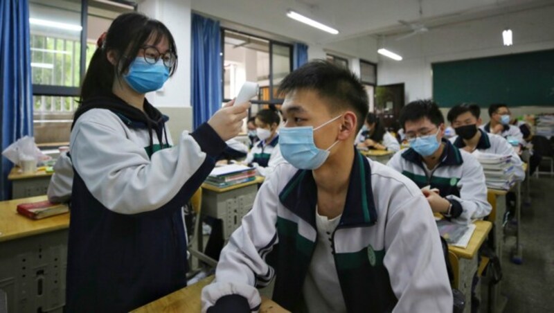 Eine Schülerin in der chinesischen Metropole Wuhan misst die Körpertemperatur eines Mitschülers. Seit Mittwoch sind die Schulen in Wuhan wieder geöffnet. (Bild: AFP)