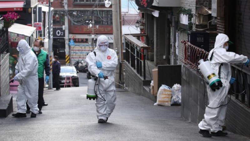 Mitarbeiter der Gesundheitsbehörde von Seoul desinfizieren die Straßen des für seine Klubs und Bars bekannten Viertels Itaewon. (Bild: AFP)