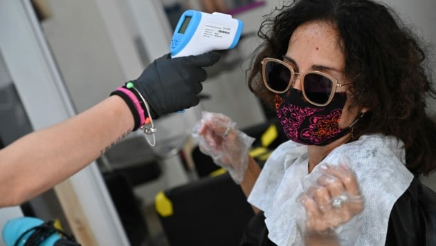 Fiebermessen beim Friseur (Bild: AFP)