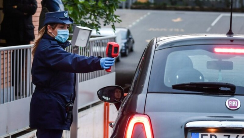 Eine Mitarbeiterin des Sicherheitsdiensts misst die Temperatur eines Fiat-Mitarbeiters beim Eintreffen im Werk des Automobilherstellers in Turin. (Bild: AFP)