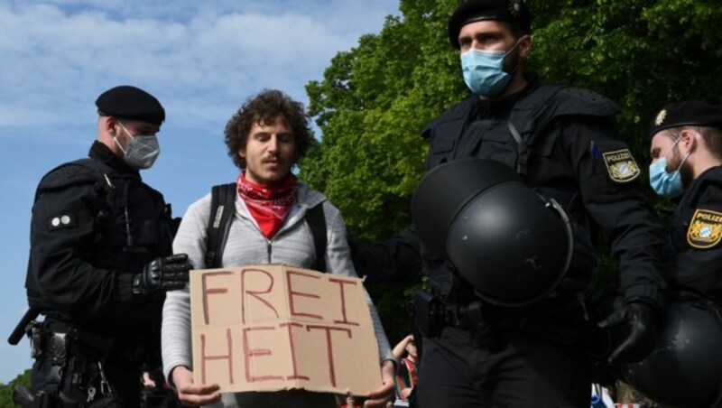 Polizisten nehmen einen Mann vorübergehend fest, der an einer unerlaubten Protestveranstaltung in München teilnimmt. (Bild: AFP)