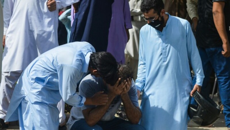 Zwei Männer trösten einen Mann, der Angehörige bei dem Flugzeugabsturz in Pakistan verloren hat. (Bild: AFP)