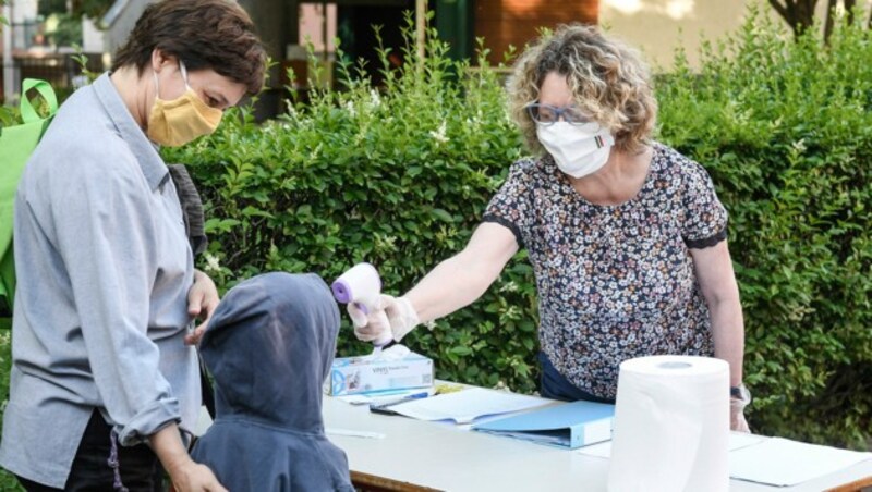 Eine Frau misst die Temperatur eines Kindes beim Eintreffen in einer Kindertagesstätte in Ivrea, Italien. (Bild: AP)