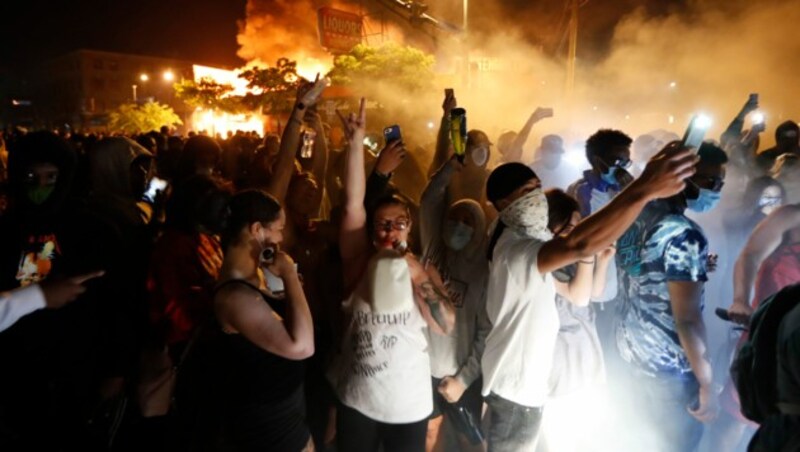 Demonstranten vor einer brennenden Polizeistation in Minneapolis (Bild: Associated Press)