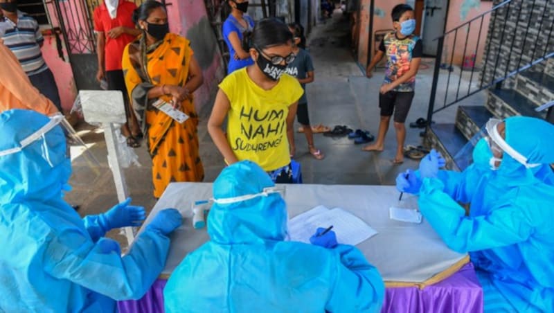 Bewohner einer Wohnungsanlage warten auf einen Corona-Test vor einem provisorisch aufgebauten Screening-Center in der indischen Millionenmetropole Mumbai. (Bild: AFP)