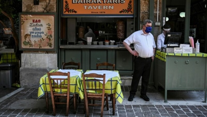 Ein Kellner mit Mund-Nasen-Schutz wartet in einem Restaurant in Athen auf Gäste. (Bild: AFP)