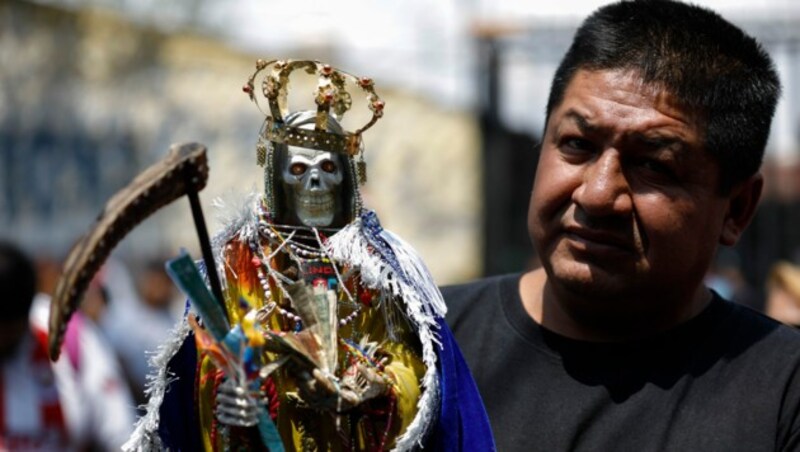 Ein Mann im Mexiko-City mit einer „Sante Muerte“-Figur während des monatlichen Gebets. In Mexiko tragen nur wenige Menschen einen Mund-Nasen-Schutz. (Bild: AP)