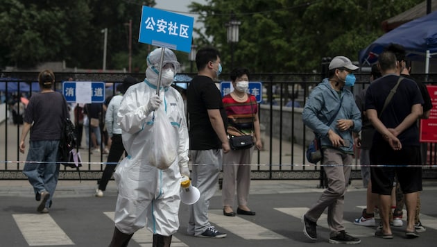 Nach dem neuerlichen Ausbruch des Coronavirus in Peking werden wieder viele Testungen durchgeführt - dieser Mann weist Bürger an, die sich testen lassen. (Bild: AFP)