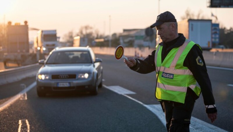 Ein slowenischer Polizist bei der Kontrolle eines Fahrzeugs aus Italien (Bild: APA/AFP/Jure Makovec)