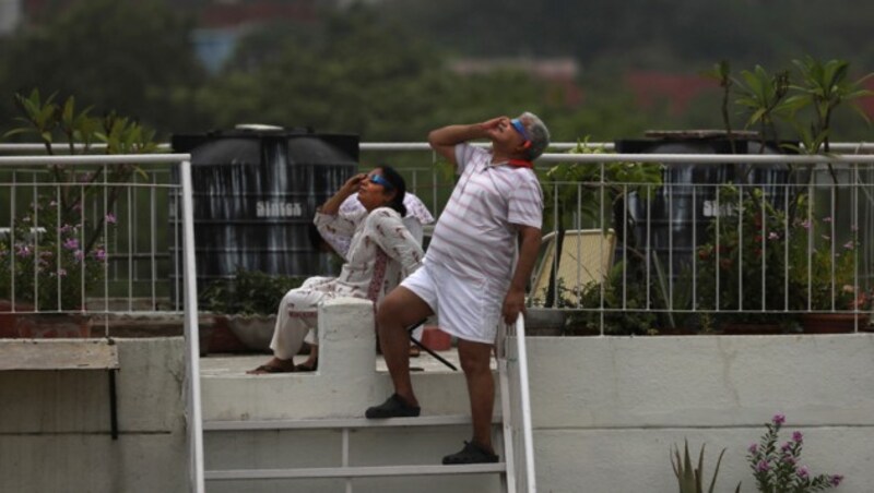 Ein Pärchen beobachtet das Spektakel in Indiens Hauptstadt Neu Delhi. (Bild: AP Photo/Manish Swarup)