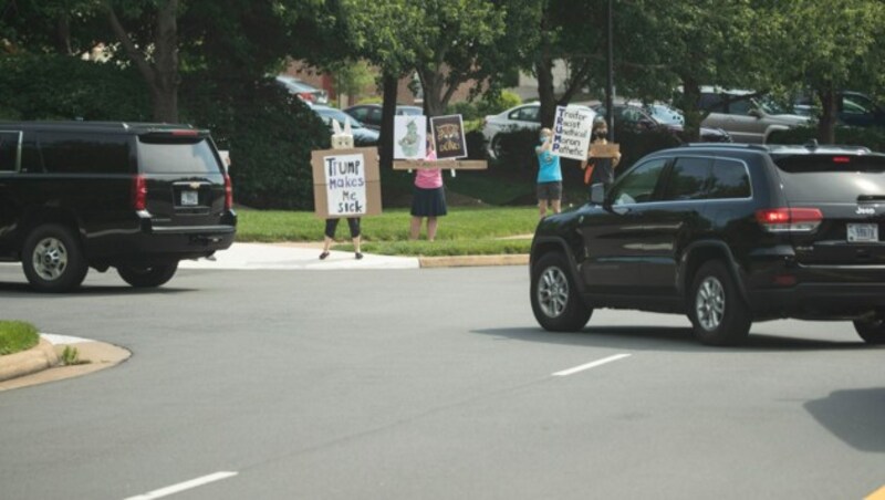 Menschen protestieren entlang der Straße, auf der US-Präsident Trump in einer Wagenkolonne zu einem seiner Golfplätze in Sterling, Virginia, unterwegs ist. (Bild: AP)