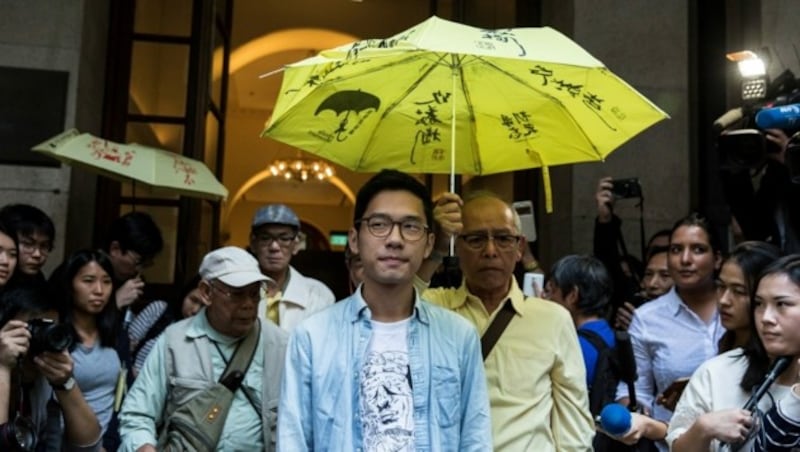 Aktivist Nathan Law (unter dem Regenschirm links) (Bild: APA/AFP/Isaac Lawrence)