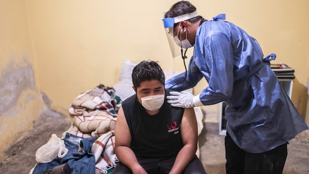 Ein Sanitäter untersucht einen Mann, der Symptome hat. (Bild: AFP )