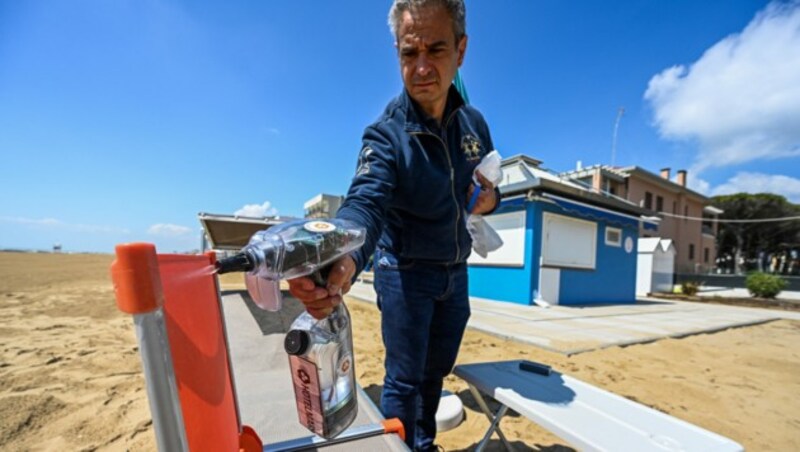 Ein Mann desinfiziert ein Sonnenbett im italienischen Urlaubsort Jesolo: Kürzlich kam eine Österreicherin mit einem positiven Coronatest aus dem Adria-Urlaub zurück. (Bild: AFP )