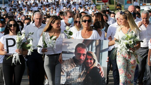 Die Frau des Busfahrers trägt ein Foto von sich und ihrem Liebsten und führt dabei den Trauermarsch an. (Bild: Associated Press)