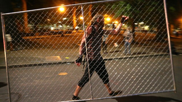 Ein Demonstrant trägt eine Absperrung weg - noch effektiver war der Protest der „nackten Athena“. (Bild: AP)