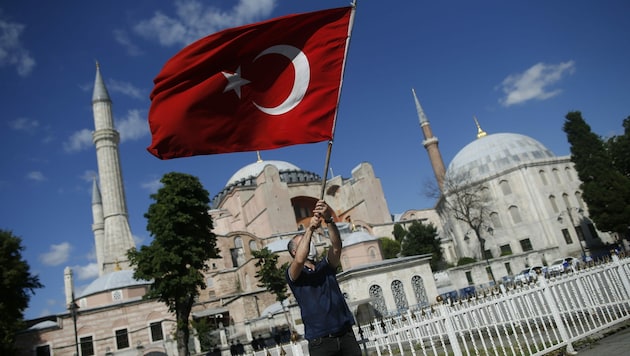 Von vielen Anhängern Erdogans wird der Schritt bejubelt. Am Bild sehen Sie einen Mann mit der türkischen Flagge vor der Hagia Sophia. (Bild: AP)