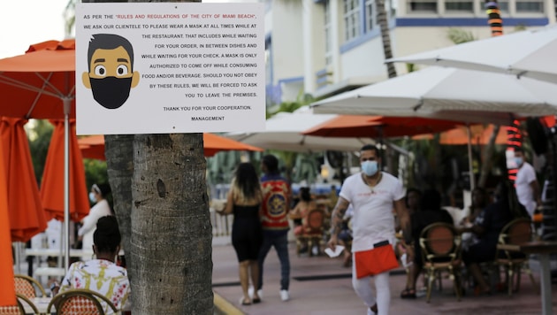 Ein Hinweis zum Tragen von Schutzmasken am Ocean Drive in Miami Beach, Florida (Bild: AP)