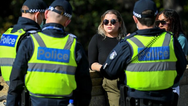 Die Polizei in Melbourne verteilt Strafzettel an zwei Frauen, die - entgegen der Vorschriften - keine Gesichtsmaske in der Öffentlichkeit tragen. (Bild: AFP)