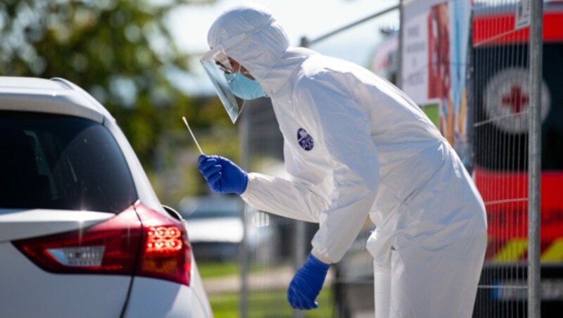 Ein Mitarbeiter des bayrischen Roten Kreuzes nimmt bei einem Testzentrum an der Autobahn einen Abstrich. (Bild: APA/dpa/Sven Hoppe)