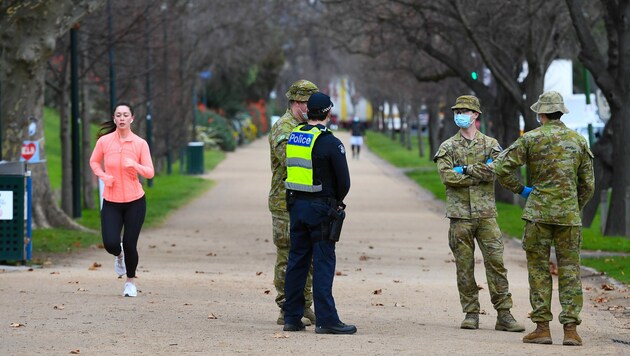 Polizisten und Soldaten patrouillieren in Melbourne auf einer beliebten Laufstrecke. (Bild: APA/AFP/William WEST)