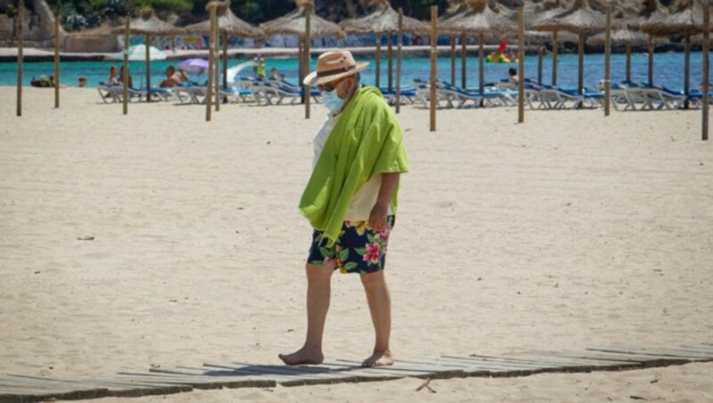 Tourist mit Maske am Strand von Mallorca (Bild: AFP)