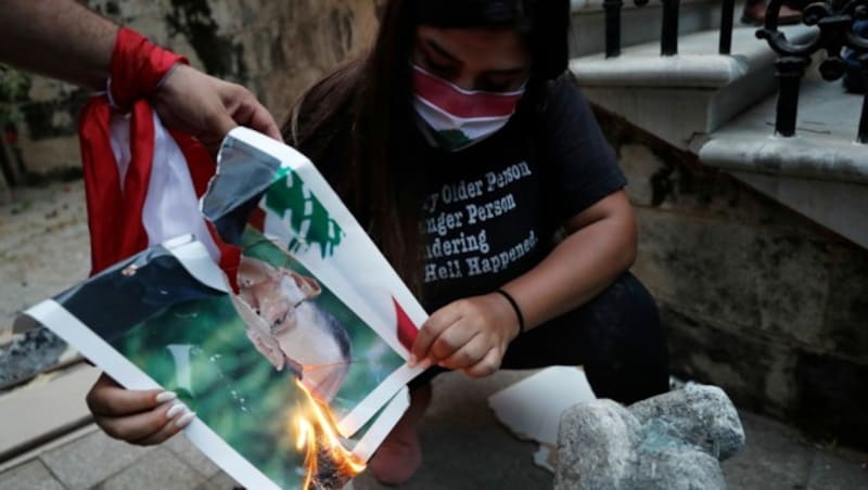 Demonstranten verbrennen ein Bild des libanesischen Präsidenten Michel Aoun. (Bild: AP)