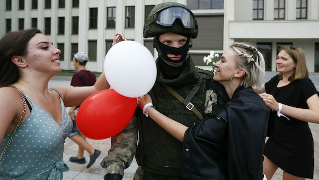 Aus Solidarität mit den Menschen senkten Soldaten am Regierungssitz ihre Schilde, Frauen schenkten ihnen Blumen. (Bild: AP)