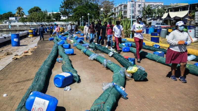 Freiwillige helfen beim Zusammenbauen von Öl-Barrieren, die das ausgelaufene Öl absorbieren sollen. (Bild: AFP)