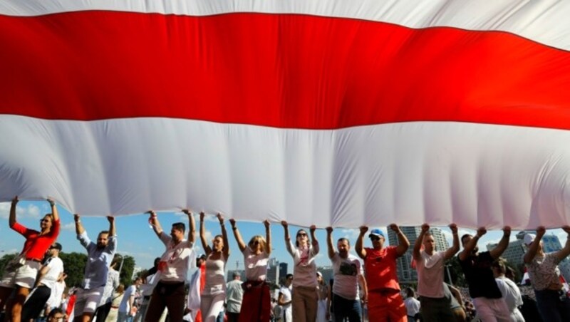 Die Demonstranten in Minsk trugen eine 100 Meter lange rot-weiße Fahne durch die Stadt. Bei dieser handelt es sich um die von Lukaschenko abgeschaffte Flagge der Nachwendezeit. (Bild: AP)