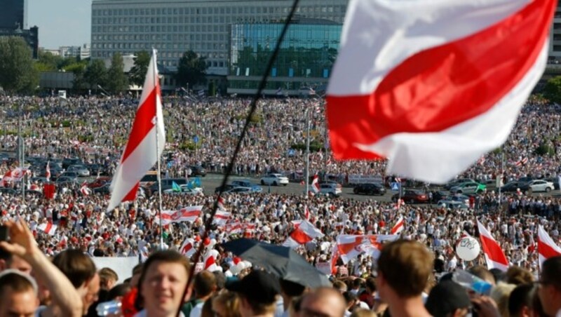 Demonstranten protestieren mit der alten weißrussischen Flagge im Herzen von Minsk. (Bild: AP Photo/Sergei Grits)