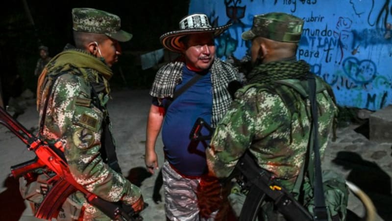Der ehemalige Kommandant der Farc-Guerilla, Juan de Dios Quintero, besser bekannt unter dem Namen „Panico“, im Gespräch mit zwei kolumbianischen Soldaten. (Bild: AFP )
