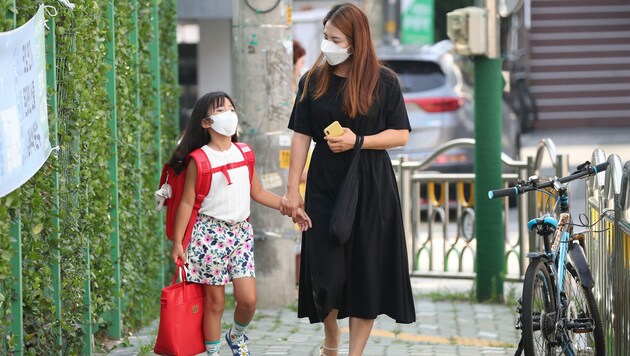 Mutter und Tochter vor einer Schule in Südkorea (Archivbild) (Bild: AFP)