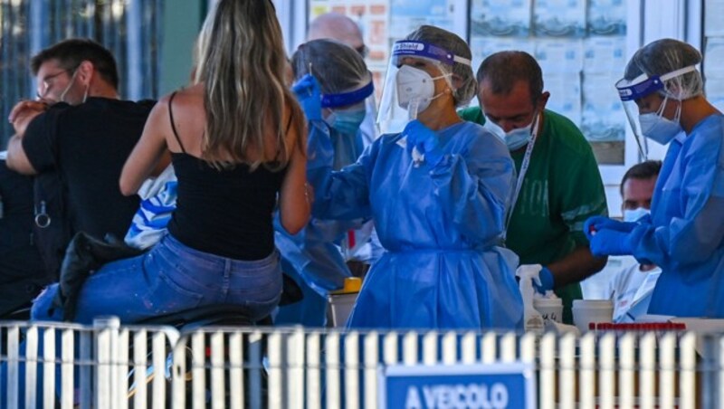 Italienische Urlauber, die von ihrem Aufenthalt auf Sardinien wieder auf das Festland zurückkehren, machen einen Test bei einer mobilen Corona-Station. (Bild: AFP)