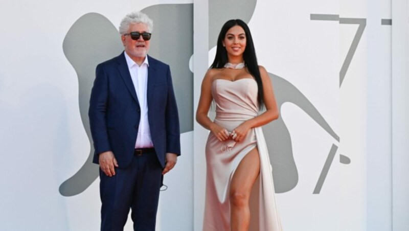 Passt perfekt zur Robe: Georgina Rodriguez mit Schutzmaske in der Hand neben Pedro Almodovar (Bild: AFP )