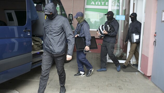 Weißrussische Einsatzkräfte bringen beschlagnahmtes Material aus einer Wohnung (Bild: AP)
