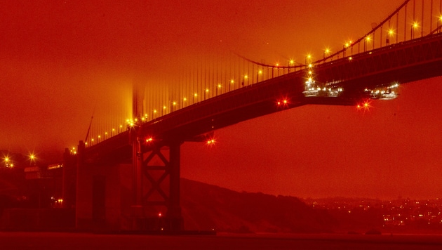 Die weltberühmte Golden Gate Bridge ist von einem dichten orangefarbenen Rauch umhüllt. (Bild: AP)