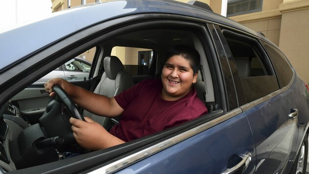 Der erst 14-jährige Ruben Navarette kann mittlerweile entspannt in jenem Auto posieren, mit dem er sich und seinen Bruder aus der Feuersbrunst retten konnte. (Bild: AFP/Frederic J. BROWN)