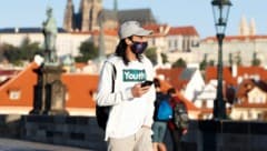 Ein Passant mit Maske auf der Karlsbrücke in Prag (Bild: AP)