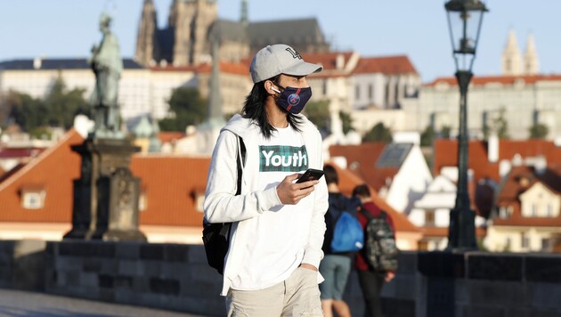 Ein Passant mit Maske auf der Karlsbrücke in Prag (Bild: AP)