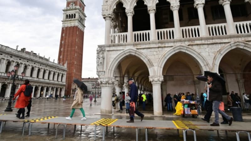 Am Markusplatz wurden erhöhte Wege errichtet, damit sich Passanten keine nassen Füße holen. (Bild: AFP)