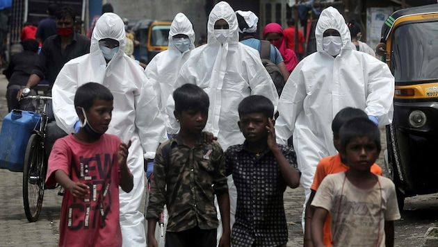 Mitarbeiter der indischen Gesundheitsbehörde unterwegs zu einem Coronavirus-Screening in Mumbai (Indien) (Bild: AP)