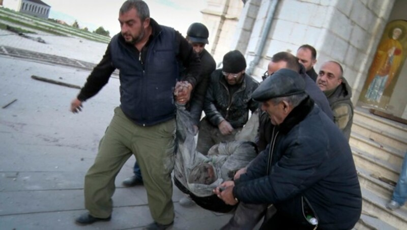 Nach einem Bombenangriff auf eine Kirche in Stepanakert (Berg-Karabach) tragen Männer einen Verletzten ins Freie. (Bild: AP)