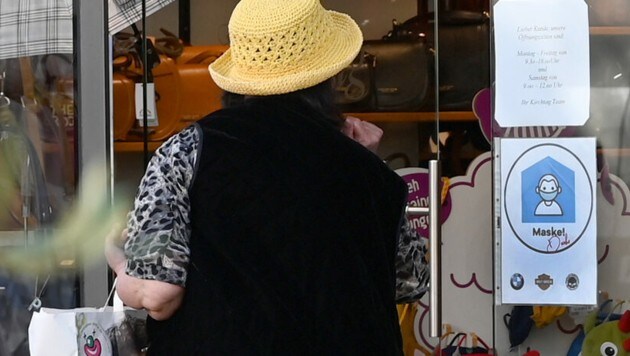 Eine Frau steht in Hallein vor einem Schild, das auf Maskenpflicht hinweist. (Bild: APA/BARBARA GINDL)